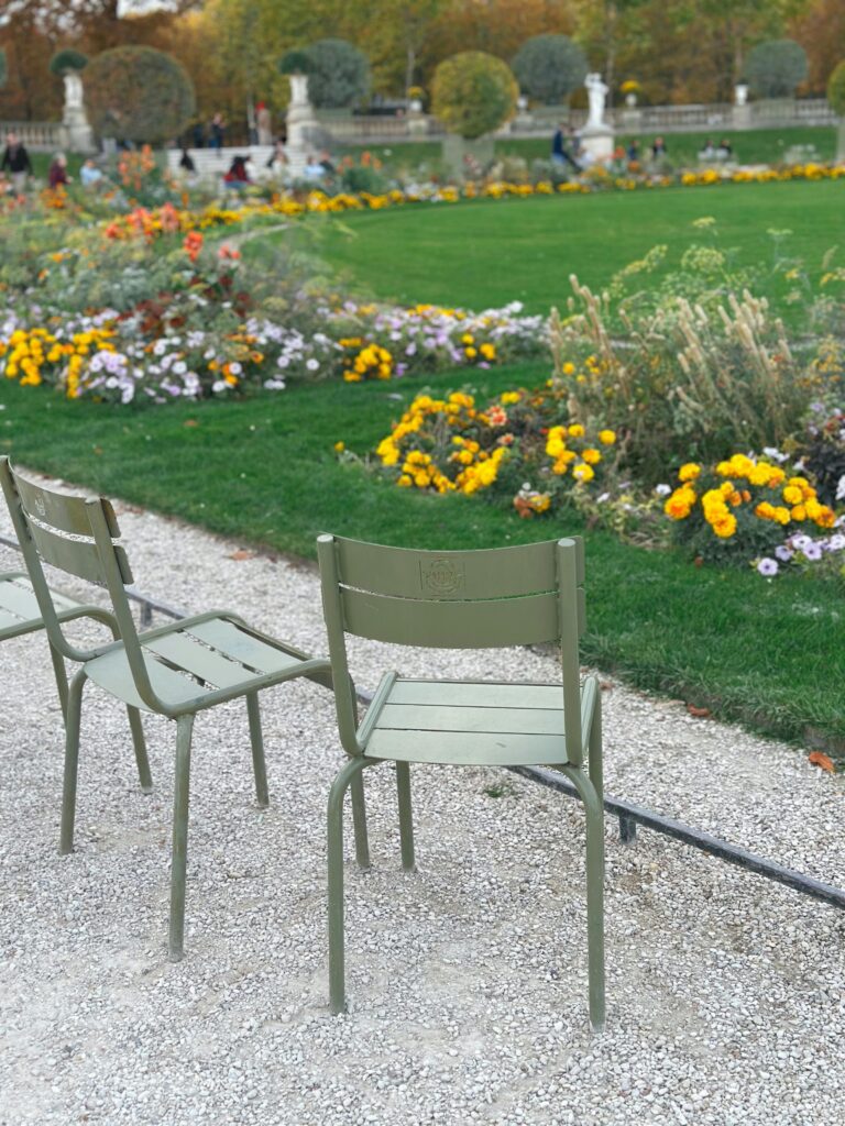 Serene autumn day in a Paris park with lush gardens and iconic green chairs.